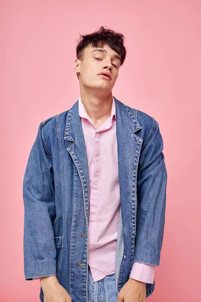 Bastante hombre en la juventud ropa elegante chaqueta de mezclilla posando fondo rosa inalterado —  Fotos de Stock