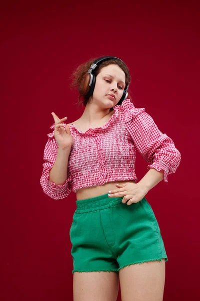 Menina alegre em uma camisa rosa ouvindo música em fones de ouvido inalterados — Fotografia de Stock