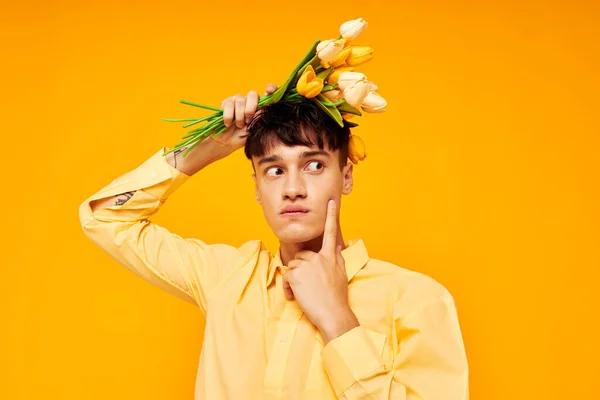 Bonito hombre dar flores desgaste gafas amarillo camisa aislado fondo inalterado — Foto de Stock