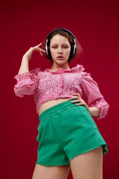 Pretty girl in green shorts moves in headphones listening to music Foto Stock Royalty Free