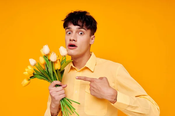 Pohledný chlap ve žlutých brýlích s kyticí květin žluté pozadí beze změny — Stock fotografie
