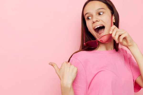 Pembe tişörtlü güzel bir kadın. Günlük kıyafetler. Pembe arka plan.