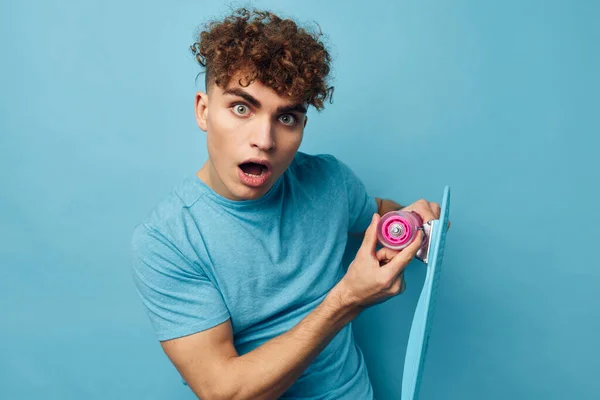 Bonito jovem homem azul skate na mão isolado fundo — Fotografia de Stock