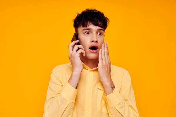 Un hombre guapo con una camisa amarilla hablando por teléfono de cerca — Foto de Stock