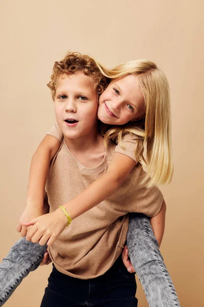 Мальчик и девочка в бежевых футболках позируют для веселого детства без изменений Стоковая Картинка