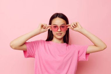 Pembe tişörtlü güzel bir kadın. Günlük kıyafetler. Pembe arka plan.