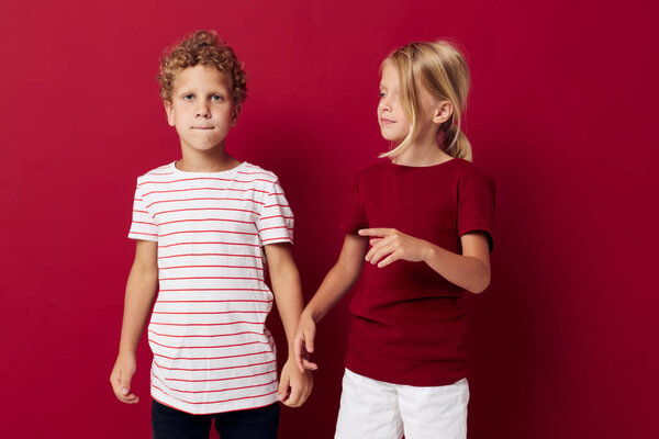 Small children emotions stand side by side in everyday clothes red background unaltered