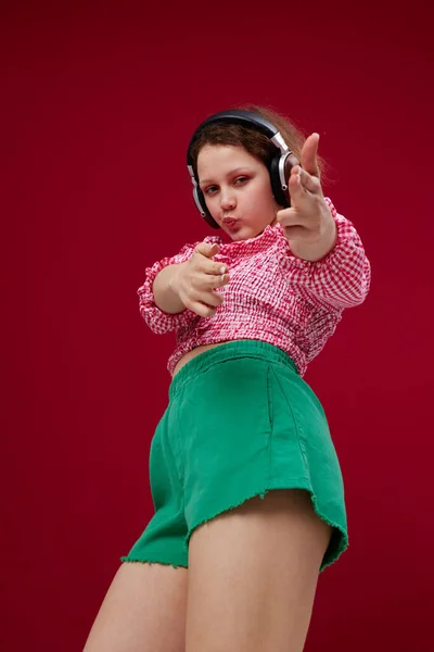 Chica emocional en pantalones cortos verdes con auriculares escuchando música inalterada —  Fotos de Stock
