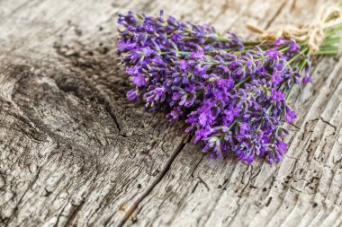 Ahşap bir masanın üzerinde kurutulmuş lavanta çiçekleri olan lavanta spa ürünleri. Tahta zemine banyo tuzu ve masaj yağı serpiştirilmiş. Cilt bakımı, güzellik tedavi konsepti. Lavendula oleum