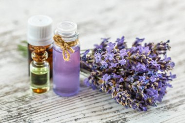 Ahşap bir masanın üzerinde kurutulmuş lavanta çiçekleri olan lavanta spa ürünleri. Tahta zemine banyo tuzu ve masaj yağı serpiştirilmiş. Cilt bakımı, güzellik tedavi konsepti. Lavendula oleum