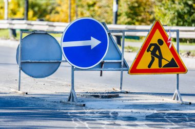 Yol işaretleri! Kamyonlar ve trafik işaretleri ile yol çalışmaları. Yol çalışmaları trafik işaretleri ve trafik konilerinin saptırma erişimini engelliyor; engeller ve trafik işaretleri.