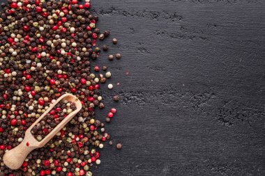 Bir biber seti. Farklı tip biber kolajı, siyah, beyaz, pembe ve tüm baharatlı biber, kurutulmuş kırmızı biber. Üst görünüm. Siyah bir arka planda. Metnin için boş yer.