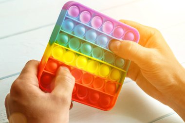 Bir erkeğin eli renkli bir gökkuşağına basar. Silikon anti-stres oyuncağı. Rahatlama, çok renkli duyusal oyuncak. Çocuklar ve yetişkinler için yeni bir duyusal stres önleyici oyuncak..