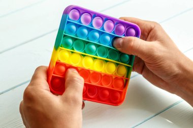 Bir erkeğin eli renkli bir gökkuşağına basar. Silikon anti-stres oyuncağı. Rahatlama, çok renkli duyusal oyuncak. Çocuklar ve yetişkinler için yeni bir duyusal stres önleyici oyuncak..