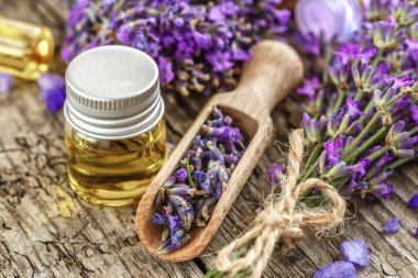 Ahşap bir masanın üzerinde kurutulmuş lavanta çiçekleri olan lavanta spa ürünleri. Tahta zemine banyo tuzu ve masaj yağı serpiştirilmiş. Cilt bakımı, güzellik tedavi konsepti. Lavendula oleum