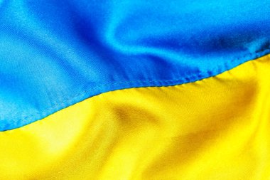Ukrayna 'nın kumaş kıvrımlı bayrağı. Mavi ve sarı renkler. Ukrayna pasaportu. Savaşı durdurun. Vatanseverlik. Ukrayna kavramı. Yakın çekim, arkaplan