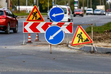 Yol işaretleri! Kamyonlar ve trafik işaretleri ile yol çalışmaları. Yol çalışmaları trafik işaretleri ve trafik konilerinin saptırma erişimini engelliyor; engeller ve trafik işaretleri.