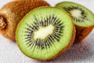 Kivi arkaplanda bir dilim kivi meyvesi. Tahta zeminde taze kiviler.