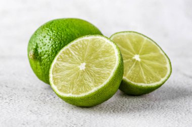 İkiye bölünmüş yeşil kireç ve beyaz arka planda izole edilmiş dilimler. Sağlıklı yeşil gıdalar - alternatif tıp vitaminler, besinler ve insan refahı için süper yiyecekler içeren dengeli bir diyet içerir..