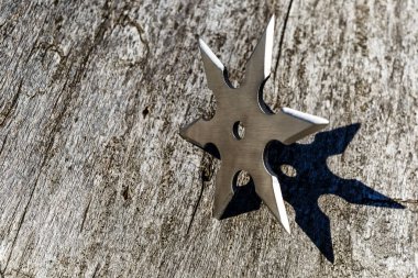 Shuriken (fırlatan yıldız), geleneksel Japon Ninja soğuk silahı tahta arka planda sıkışmış, gümüş shuriken yıldız şeklinde. Samuray, silah fırlatıyor.