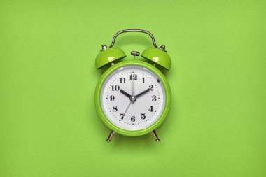 Açık yeşil arka planda yeşil alarm saati. Üst görünüm, düz görünüm, kopyalama alanı.