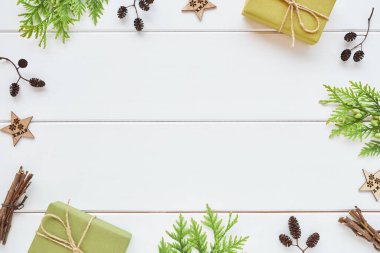 Noel ya da yeni yıl aranjmanı. Hediye kutularından yapılmış çerçeve, kozalaklı dallar ve beyaz ahşap arka planda doğal süslemeler. Düz konum, üst görünüm, kopyalama alanı.