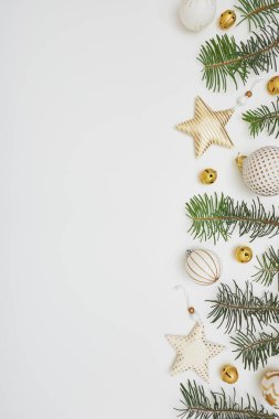 Noel veya Yeni Yıl kompozisyonu. Köknar ağacı dallarından yapılmış sınır ve beyaz arka planda altın süslemeler. Düz konum, üst görünüm, kopyalama alanı.