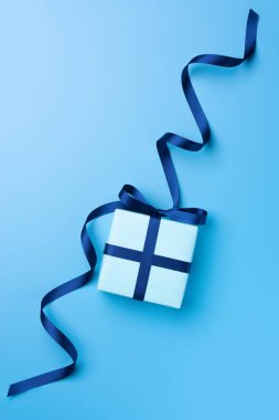 Mavi pastel arka planda parlak saten kurdeleli hediye kutusu. Üst Manzara. Boşluğu kopyala.