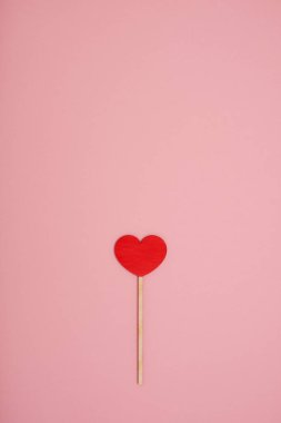 Pembe pastel arka planda kırmızı ahşap aşk kalbi.