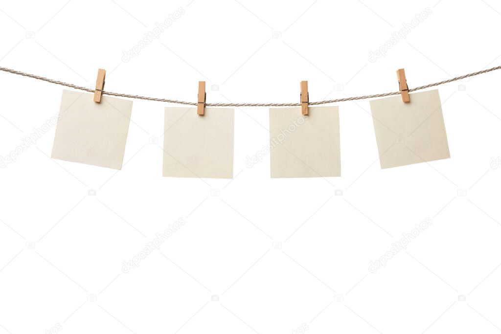 Four old paper blank notes hanging on the rope with wooden clothespins isolated on white background