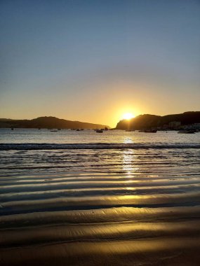 Güzel bir günbatımı ve sakin bir denizde limanda demirli tekneler.