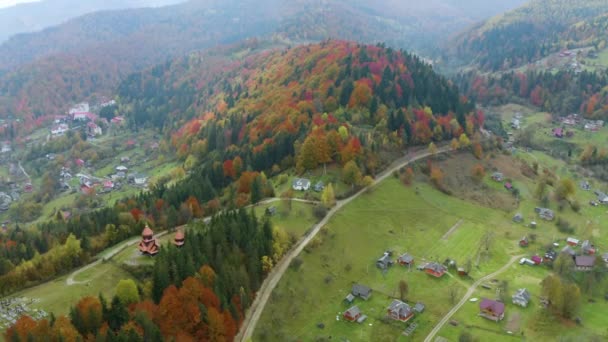 カルパチア ウクライナ 秋のブナや針葉樹林 美しい山の風景のキリスト教寺院 航空ビュードローンコプター航空ビデオ — ストック動画