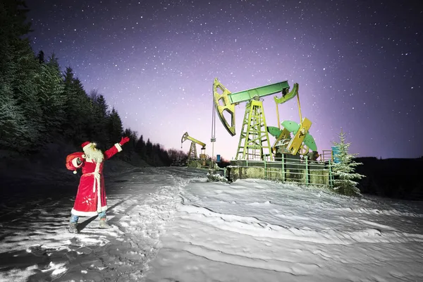 在喀尔巴阡山脉的冬季山区 圣诞老人把一袋礼物放在油泵下送给了石油和天然气工人 庆祝新年快乐的古老传统 夜空中的星空星系 — 图库照片