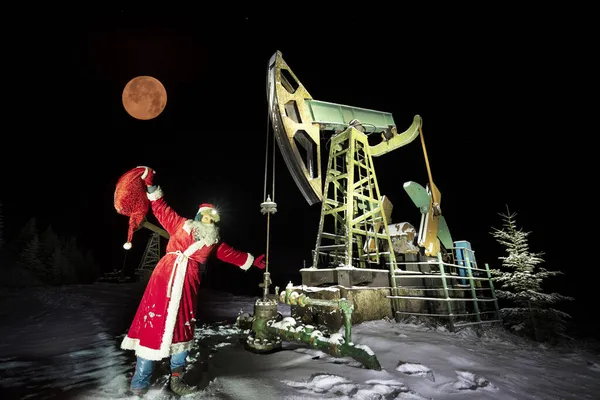 在喀尔巴阡山脉的冬季山区 圣诞老人把一袋礼物放在油泵下送给了石油和天然气工人 过年快乐的古老传统 — 图库照片