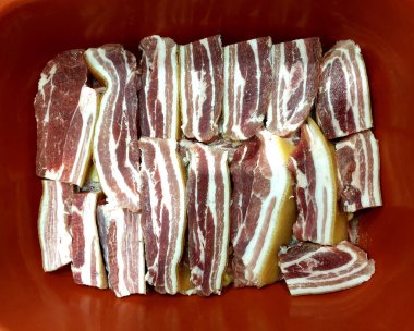 Tuzlu domuz eti, pastırma, kırmızı arka planda çizgili.