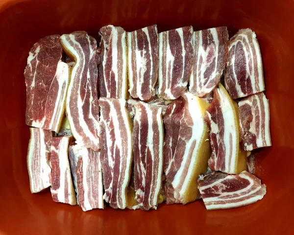 Tuzlu domuz eti, pastırma, kırmızı arka planda çizgili.