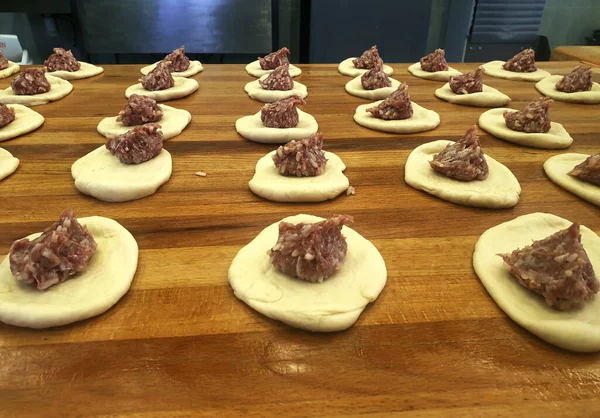 Tahta bir masada etle turta yapma süreci.