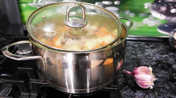 Mutfakta çorba ve sobanın üstünde çelik tava.