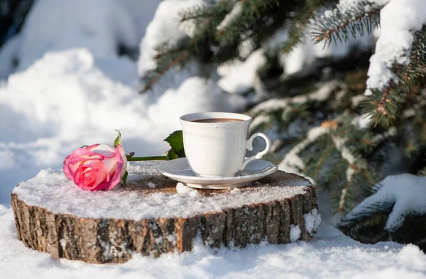 a cup of coffee in the snow with a rose
