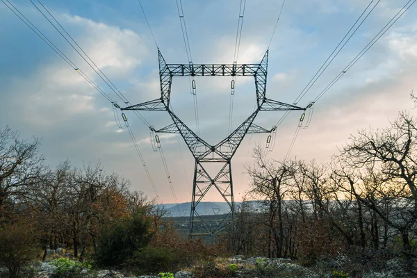 high voltage electric line stretching between the mountain peaks during the setting sun
