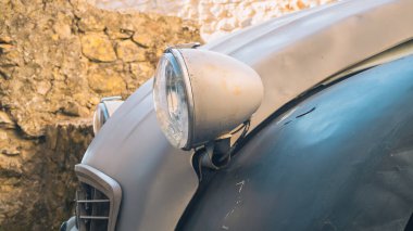 A close-up of the front of an old Citroen 2 CV, headlamp and hood in the first frame. The 2cv model is not longer in production and considered a collector's piece. Vintage car