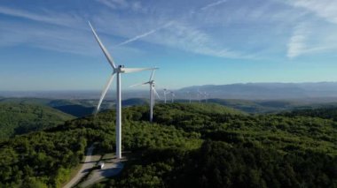 Enerji üretimi için türbin yel değirmenleri. Yenilenebilir enerji kaynakları. Ağaçlarla kaplı bir tepede bulunan yel değirmenleri. Çevredeki dağlara bakıyor. Drome - Güney Fransa