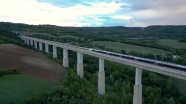 Drome, Fransa - 24 Eylül 2022: Yolcu TGV treni La Roche-Sur-Grane (Drome - Fransa) yakınlarındaki tünele giriyor. Tepedeki rüzgâr tarlasına bakan