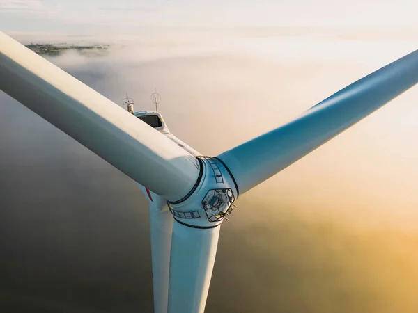 Close-up on the propellers of a wind turbine during a misty morning and sunrise. Green energy. Wind turbine at morning fog