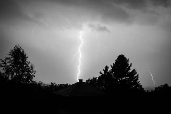 Czarno-biały piorun uderzył w dom i las w Bułgarii. Piękna potężna ciemna burza. — Zdjęcie stockowe