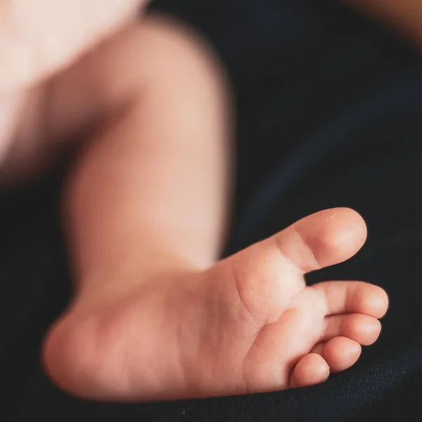 Ноги новорожденного на тёмном фоне. Новорожденные детские пальцы закрываются, избирательный фокус. — стоковое фото