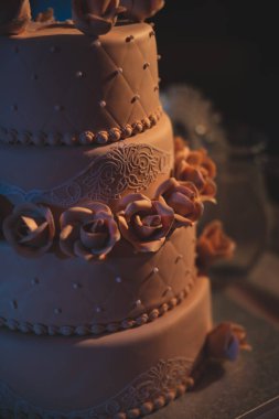 Kahverengi, üç katlı güllü bir düğün pastası. Lezzetli bir kutlama pastası..