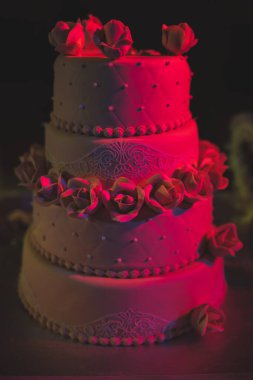 Kahverengi, üç katlı güllü bir düğün pastası. Lezzetli bir kutlama pastası..