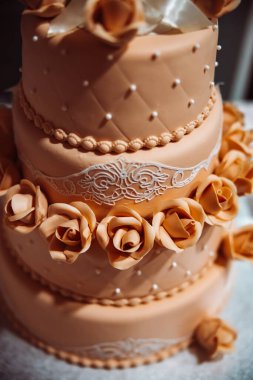 Kahverengi, üç katlı güllü bir düğün pastası. Lezzetli bir kutlama pastası..