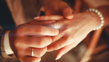 Düğün için. Karanlık arka plandaki erkek ve kadının elleri ılık, yumuşak güneş ışığında. Yeni bir aile doğdu..